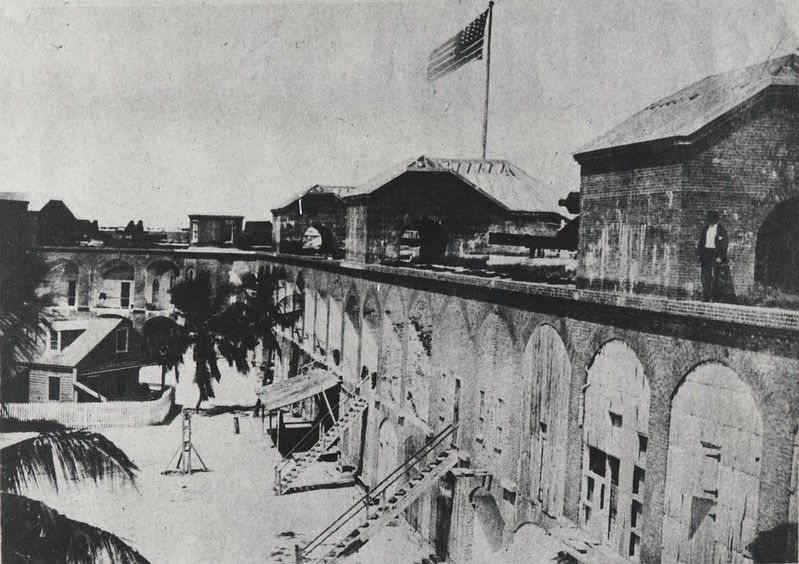 The interior of a fort with several sets of stairs leading to the second level and an American flag flying from the top.