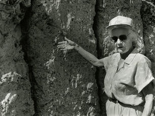 A woman gestures at a rock wall