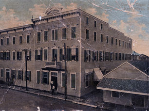 A large three story building with a sign on the roof that reads Cortez Cigar Co.