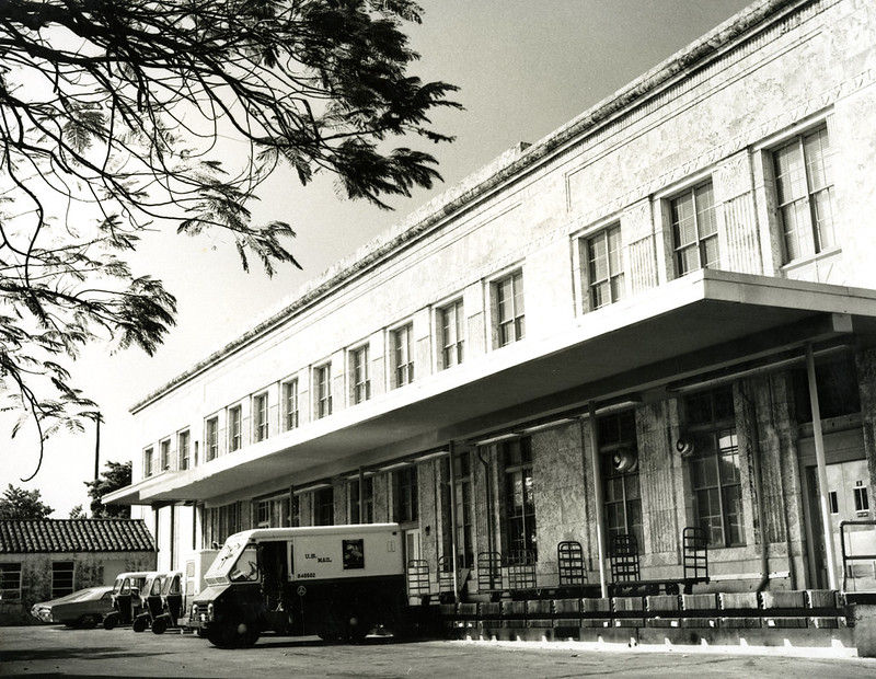 a long building with u.s. mail trucks backed up to it.
