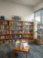 W book shelf with books and gifts as well as a table with displaye dbooks and a card rack.