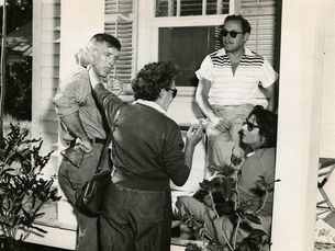 Four people sitting and standing on a porch