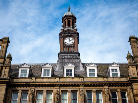 A grand building with a clock tower and a blue sky in the background. 