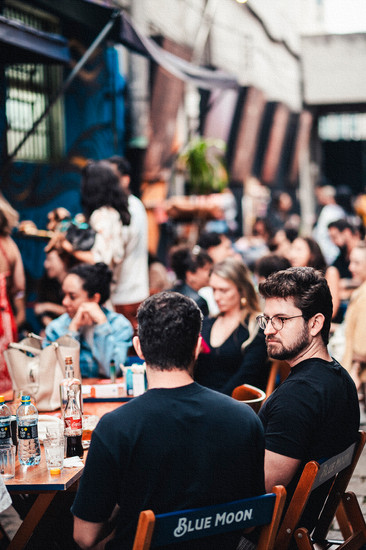 Pessoas sentadas ao ar livre, bebendo e convesando.