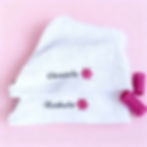 Serviette à cheveux blanche brodé du prénom en noir et d'une petite fleur fuchsia.