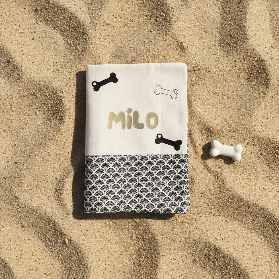 Le protège carnet est en tissu blanc sur le haut et à motifs géométriques noirs et dorés sur le bas.