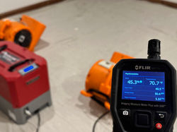 hygrometer moisture meter and air movers drying a water damage basement ceiling