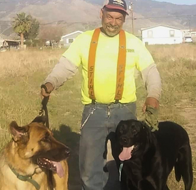 A man with 2 dogs. 1 german shepherd and 1 lab.