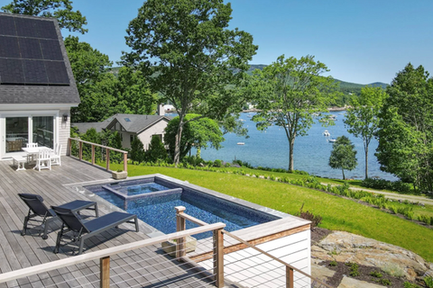 Outdoor pool with ocean view, trees, and blue water, Dirigo Pools.