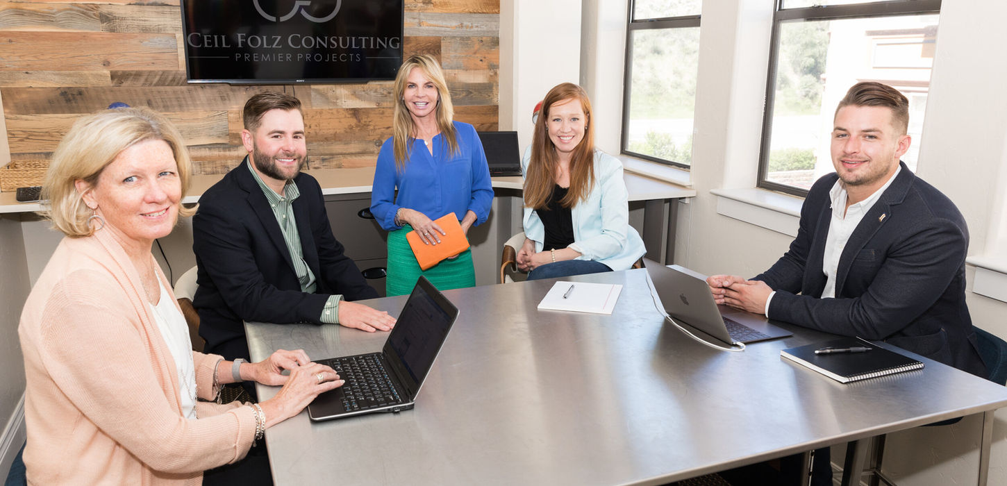 Five smiling professionals at a modern office meeting