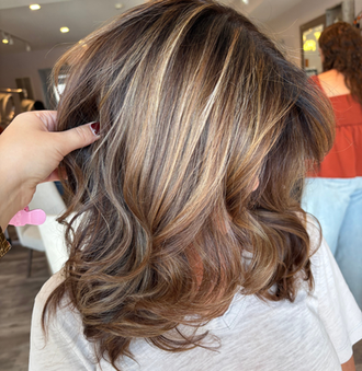 Woman's brown and blonde highlights, styled hair, hands holding it, Salon M on Hudson