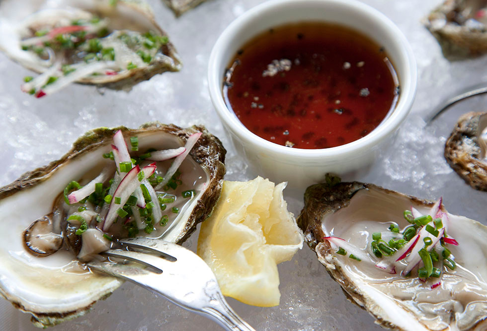 Photo of Oysters on the Half-Shell with slice of lemon and black pepper ponzu sauce.