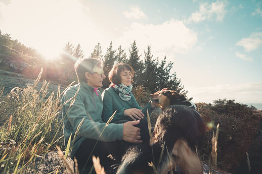 two-people-and-their-pet-dog-sit-on-a-rock-in-a-hill.jpg