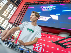 ein DJ mit Mischpult und Leinwand im Hintergrund