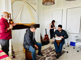 3 men playing different kinds of instruments with two of them being drums