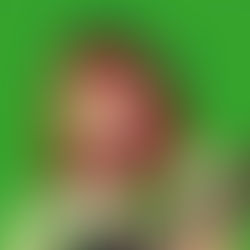 Red-haired woman with a green beret and matching dress holds a guitar against a vibrant green background. Her expression is thoughtful.