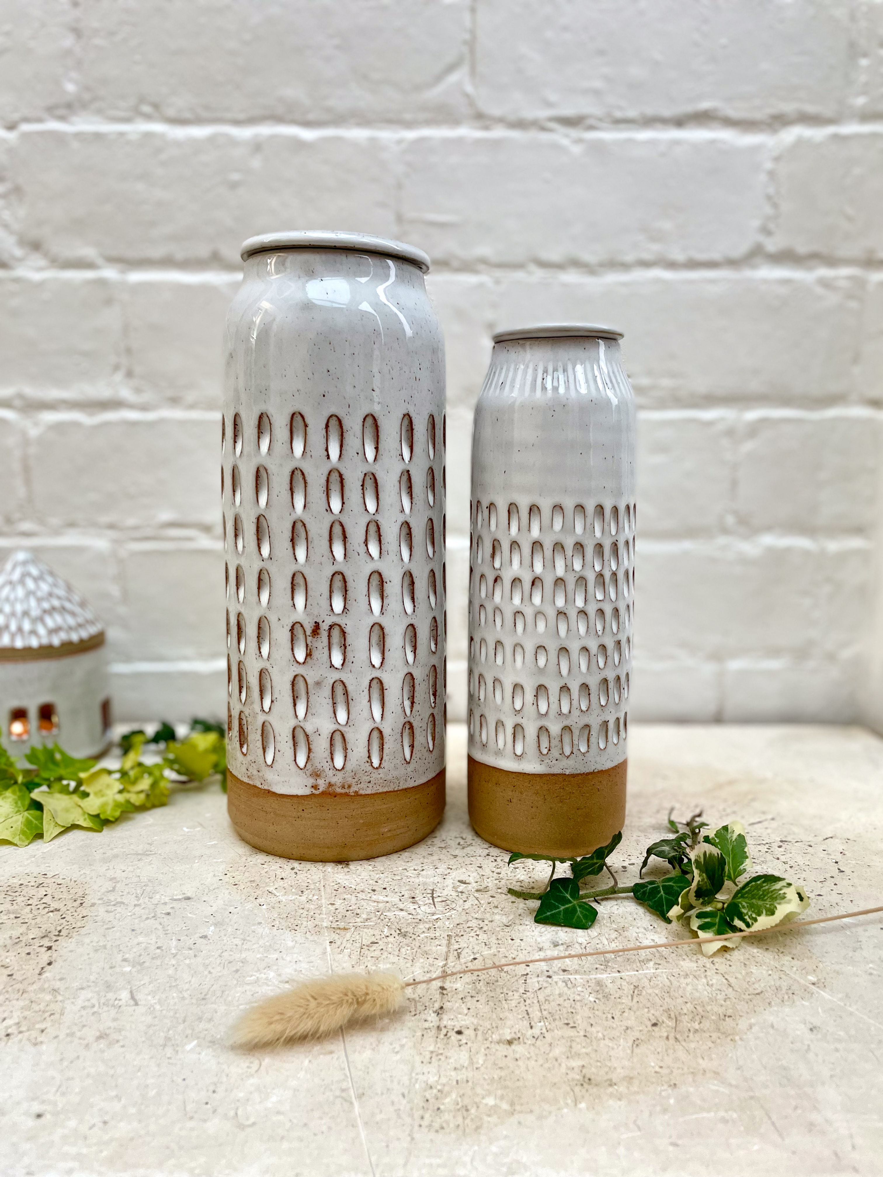 Tall carved ceramic lidded storage jar in white.