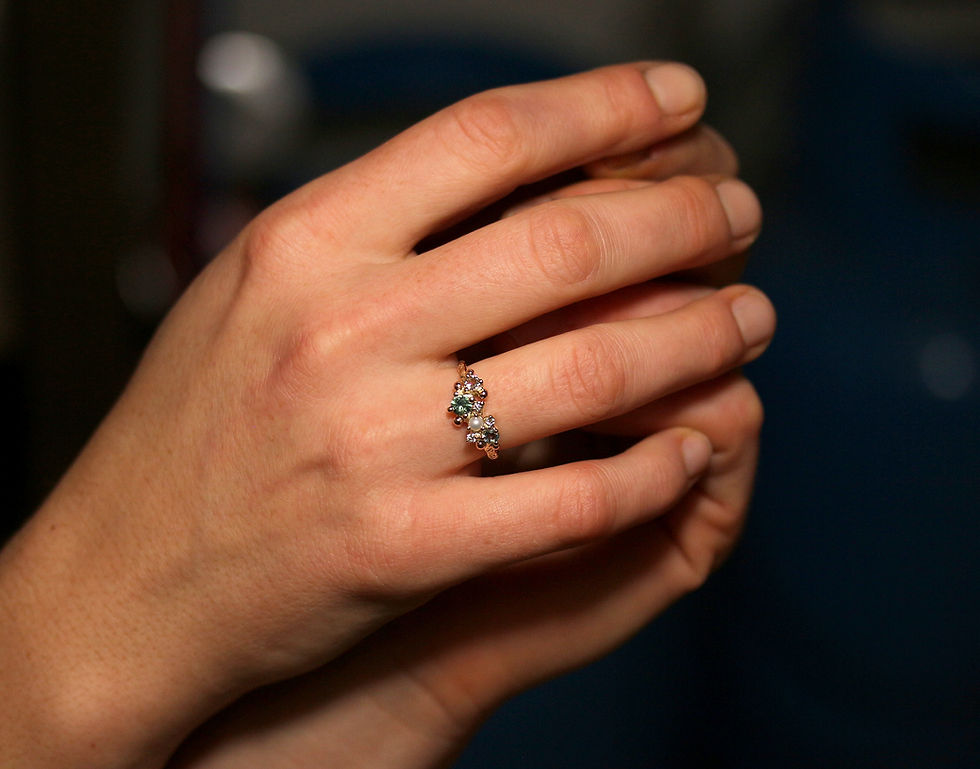 Thumbnail: Sleek structured gold ring with various gemstones on a hand