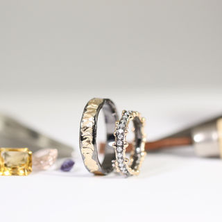 Gold wedding rings, with black rhodium border. Women'a has diamonds on the upper half of the ring.