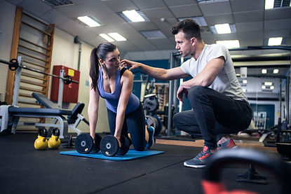 Personlig træner hælper en kvinde med sin stilling