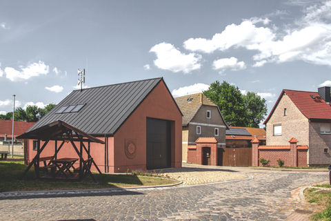 Ein Neubau einer Feuwehrgarage mit dunklem Dach und roter Putzfassade