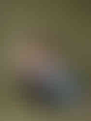 Mother and daughter sitting close together barefoot, wearing cozy knits and jeans against an olive green backdrop in a studio photography session