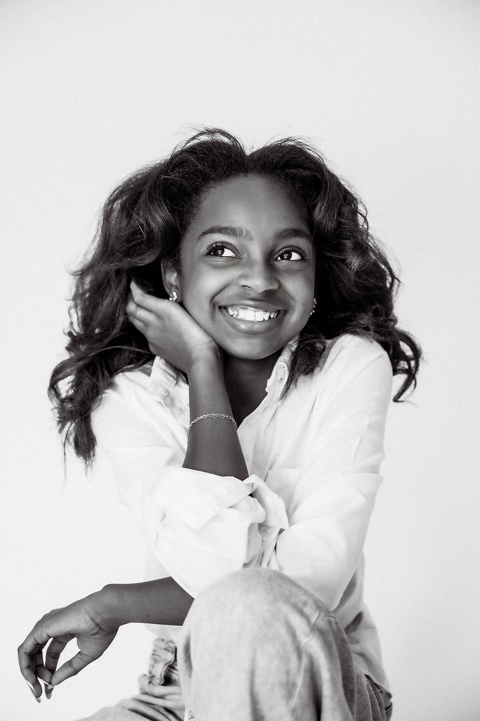 Black and white portrait of a tween girl laughing and looking away, captured mid-giggle during a joyful milestone shoot