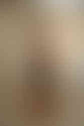 Full-body studio portrait of a woman seated confidently on a stool, wearing a brown top and leather pants, photographed against a warm neutral backdrop by Geni Bean Portraits, a branding photographer in North Carolina.