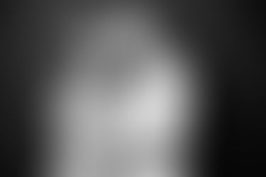Black and white image of mother daughter pictures session where a mother and daughter wearing tweed tops hug closely in front of a dark backdrop and smile softly