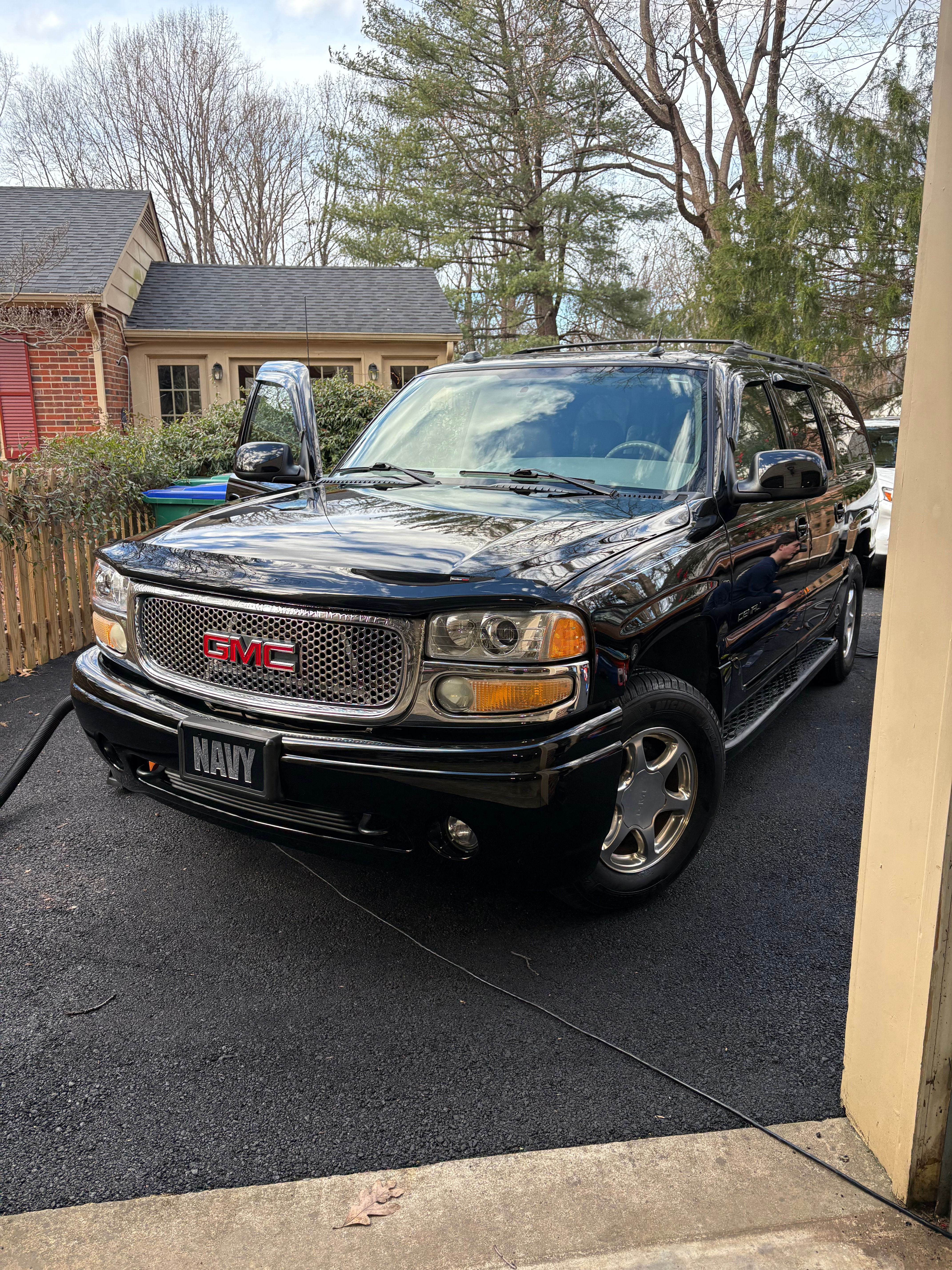 Black GMC Yukon with NAVY license plate parked outside a house.