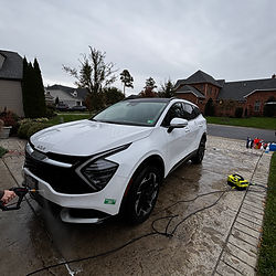White Kia Sportage being washed on a driveway with cloudy background