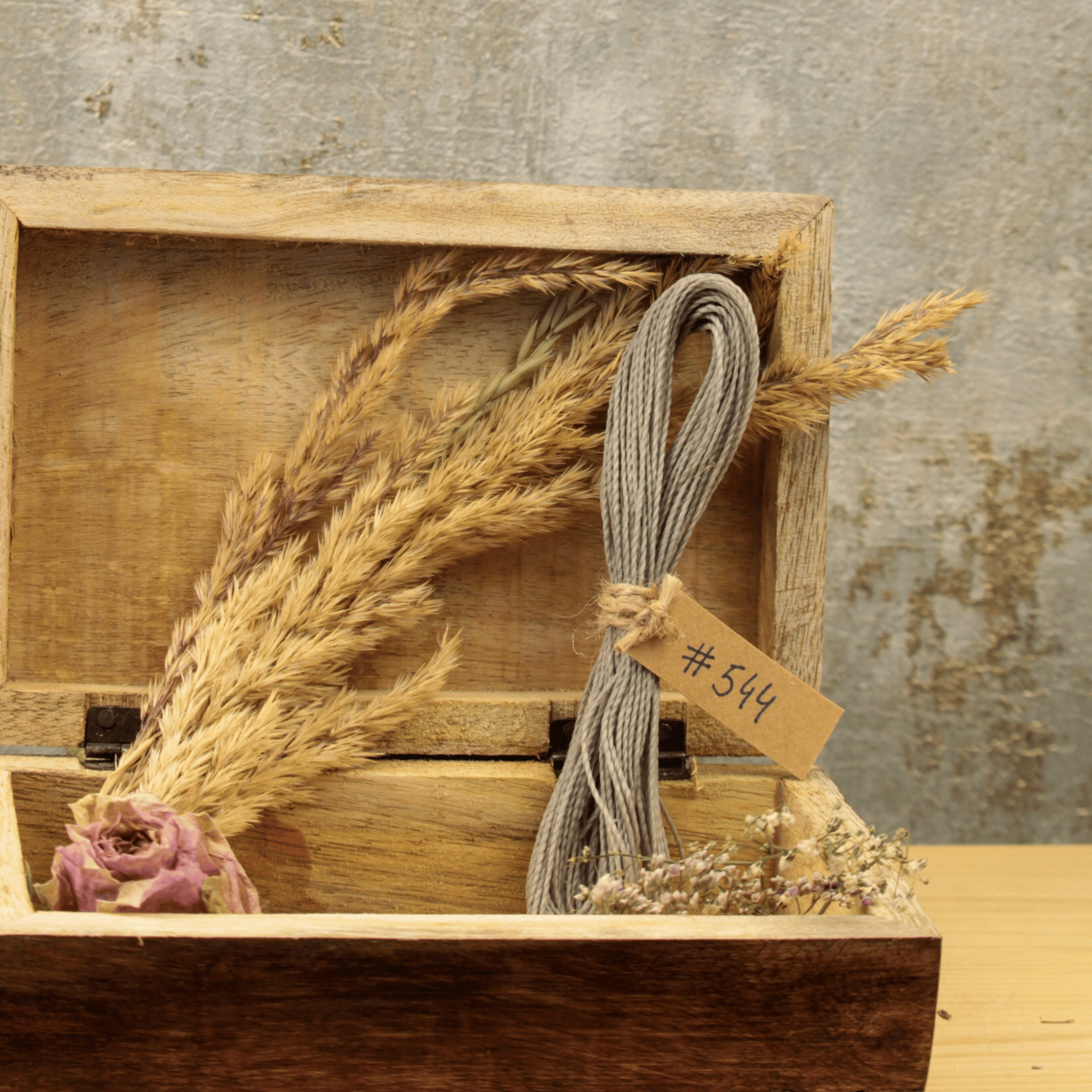 Linhasita Makramee Garn Stärke 1mm in einer Holzbox mit Trockenblumen, nachhaltiges Material für handgeknüpften Schmuck.