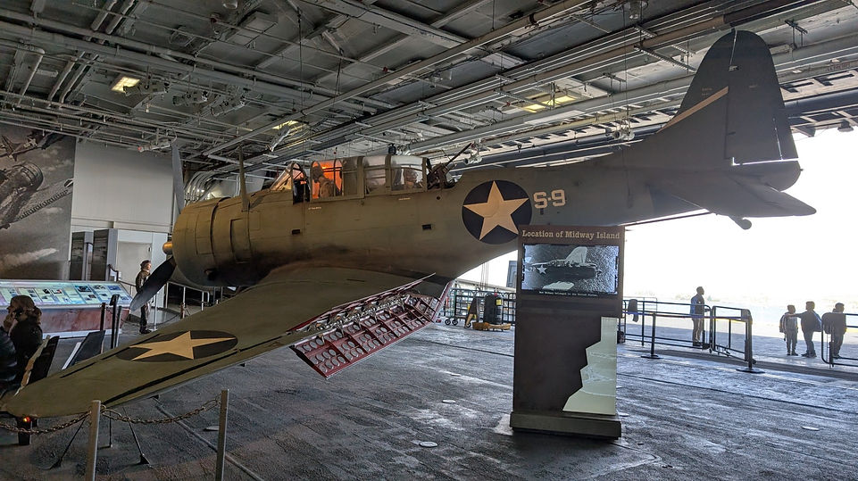 Douglas SBD Dauntless dive bomber on display, a two-seat WWII naval aircraft with distinctive perforated dive flaps