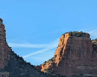 Red sandstone buttes and mesas rising above green desert vegetation near Oak Creek Village.