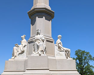 The tall granite Soldiers' National Monument in the Gettysburg National Cemetery features allegorical figures of Liberty, War, and Peace.