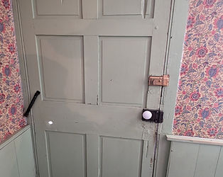 A close-up of the original wooden door of the Jennie Wade House, showing multiple visible bullet holes from the battle.