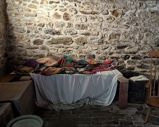 A dim basement room at the Jennie Wade House, staged with period-appropriate storage barrels and a small cot.