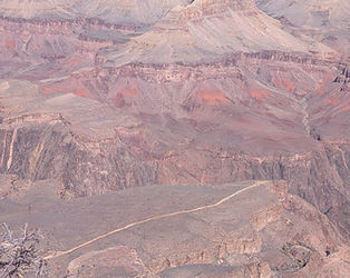 The Colorado River winding through the inner gorge at the bottom of the canyon, surrounded by steep, dark metamorphic rock walls.