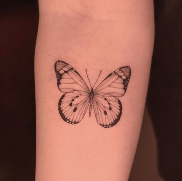 Tatuagem de borboleta em estilo fineline delicado no braço
