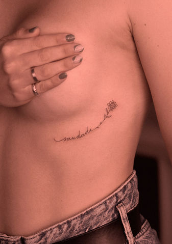 Tatuagem de palavra saudade com flores na costa em fineline