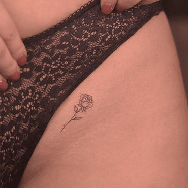 Tatuagem feminina de rosa minimalista na virilha