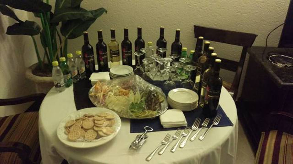 Picture of a table set up with wine, cheese, crackers and fruit for a cocktail party.