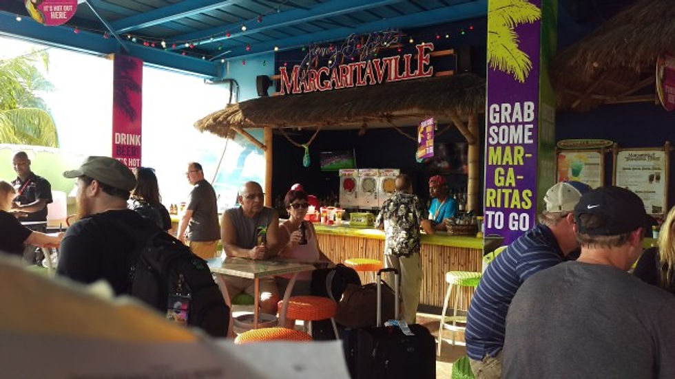 A picture of the Margaritaville bar on the outside of the airport with people sitting around and having drinks.