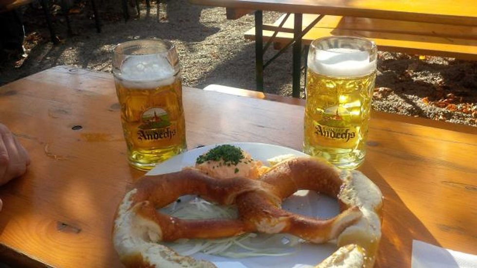 A picture of a giant pretzel on a plate and two beers.