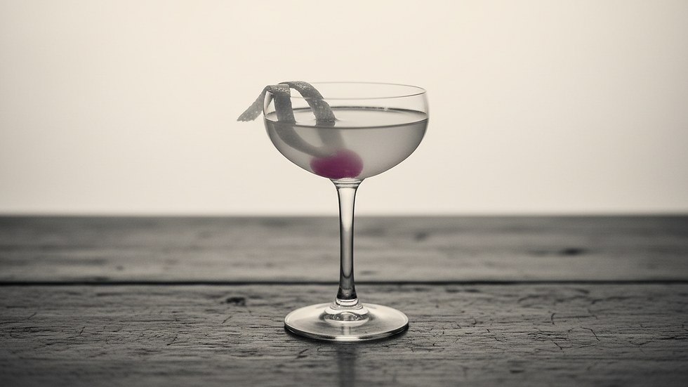 Close-up of a coupe glass with a lemon twist garnish on a vintage wooden table