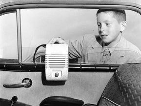 Young boy searches for the perfect spot to hang drive-in movie theatre window speakers before an evening film screening.