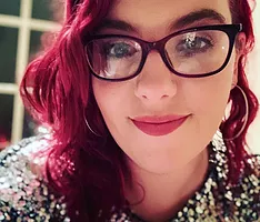 Melissa Gray - Owner Of Wild Child Studio, with pink hair and a silver glittery dress.