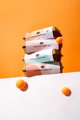雞蛋品牌商品攝影作品，展示品牌包裝設計與蛋品擺設情境。以橙色與白色為主調，營造溫暖清新的品牌氛圍。由知覺攝影工作室拍攝，展現產品質感與品牌視覺一致性。