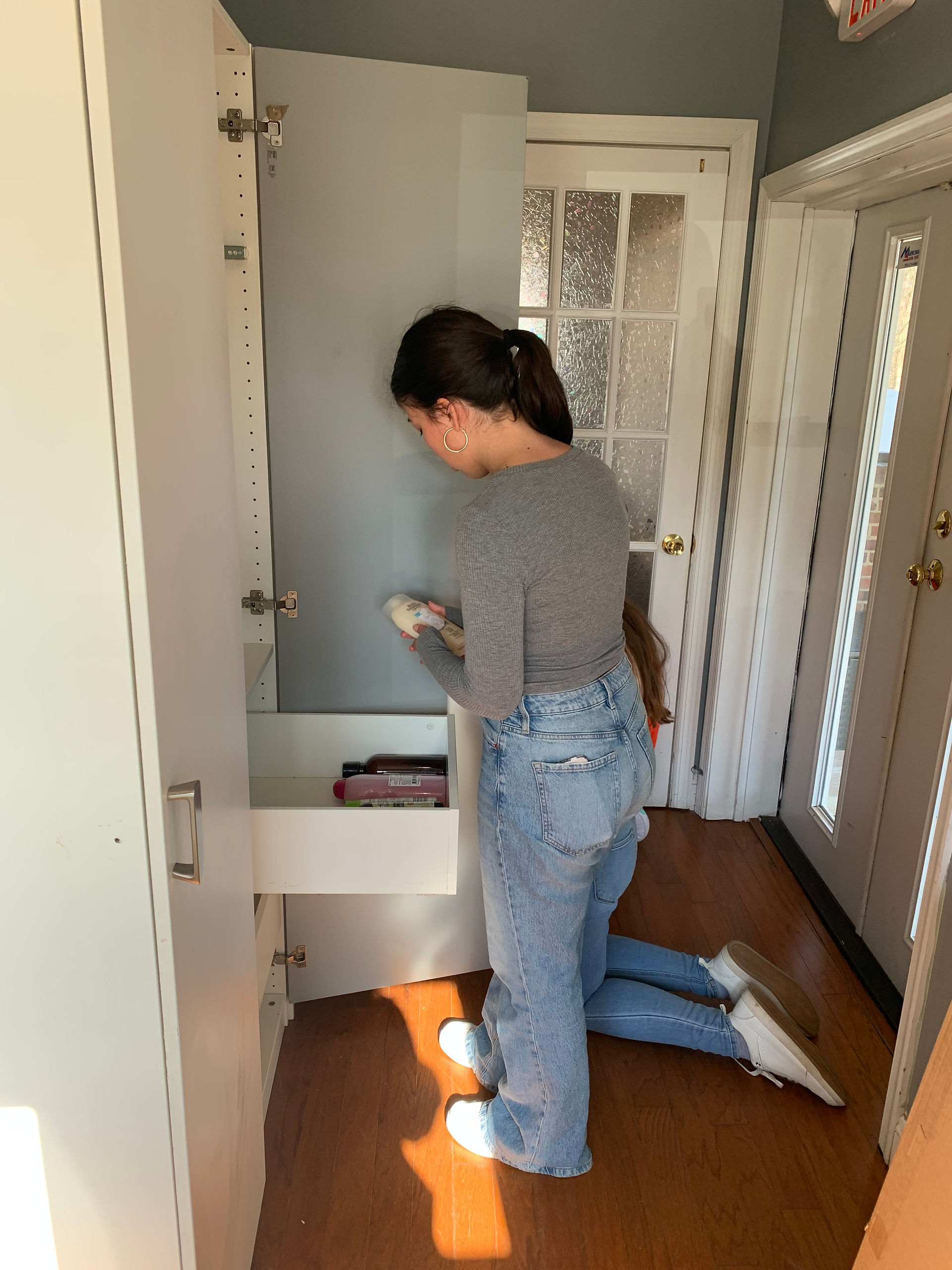 Girl organizing toiletries in a closet.