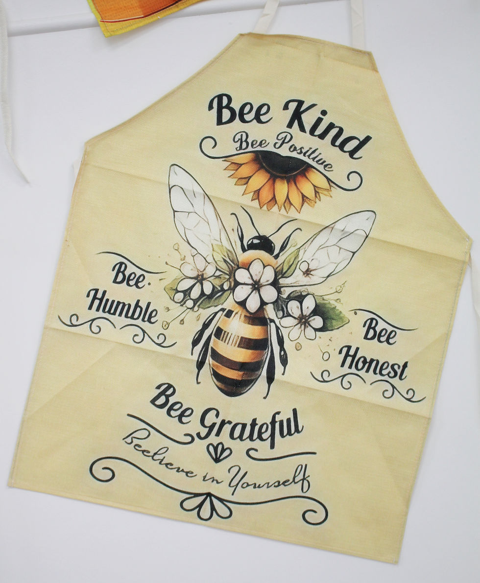 Yellow apron with a bee illustration surrounded by flowers. Text reads: "Bee Kind, Bee Positive, Bee Humble, Bee Honest, Bee